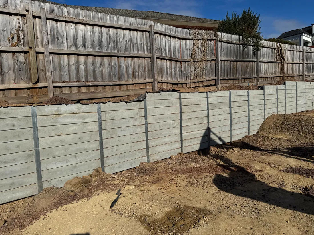 Finished grey sleeper retaining wall in a backyard