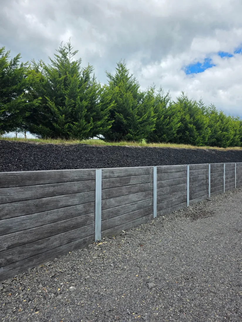 Finished charcoal woodgrain retaining wall along a driveway