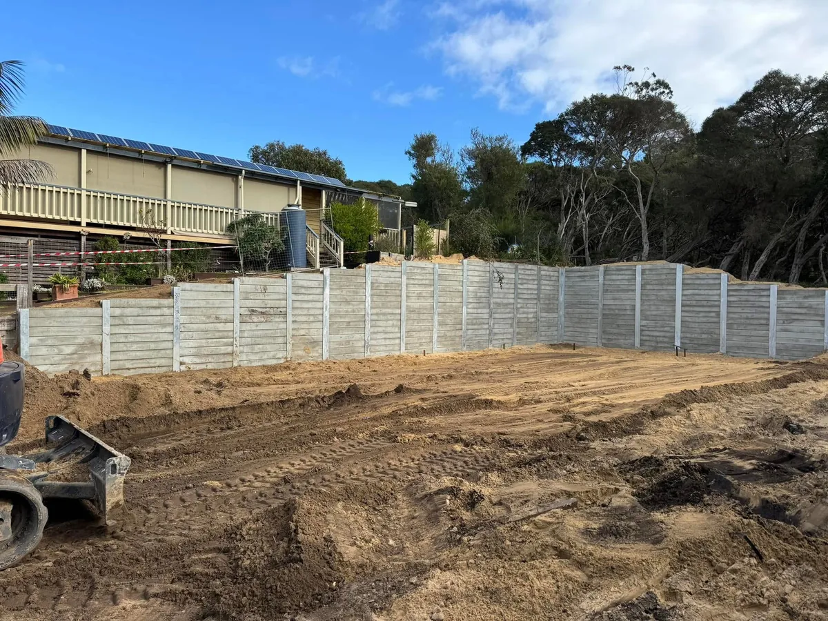 Long grey sleeper retaining wall running the length of a home on a coastal block