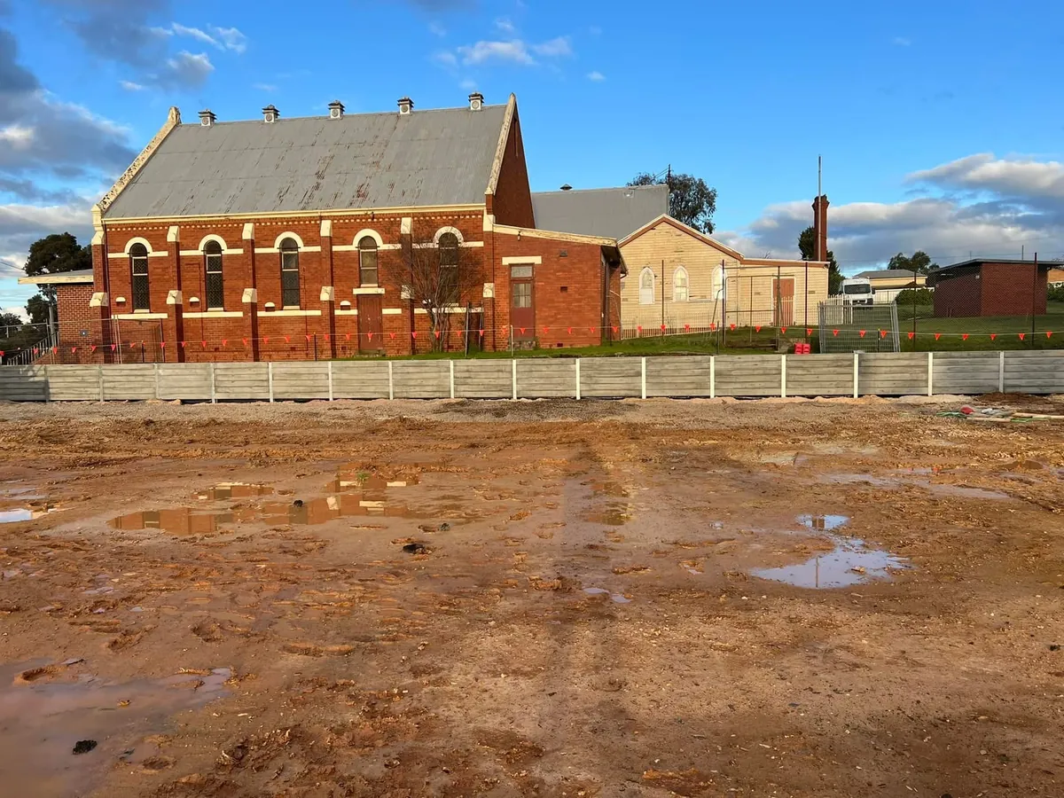 Retaining wall along the boundary of a heritage red-brick hall