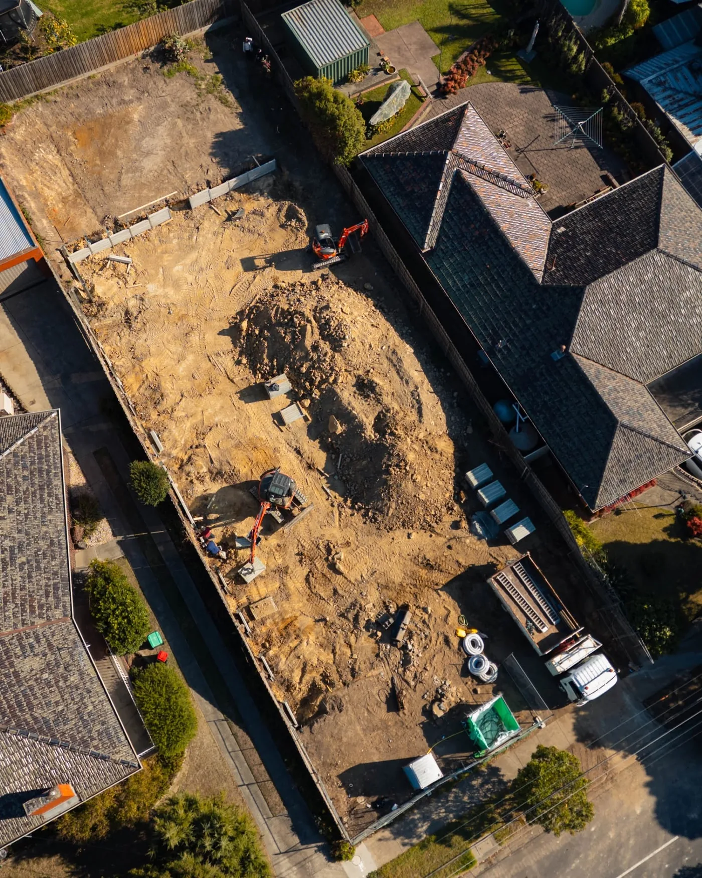 Aerial view straight down over a residential block with two Align excavators cutting the pad and the wall line set out